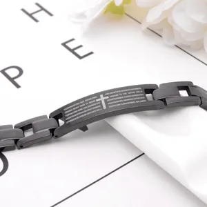Men's black titanium steel bracelet with cross engraving and religious text detail closeup.