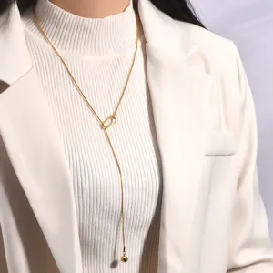 Detaillierte Ansicht der eleganten goldenen Y-Kette, getragen auf einem weißen Pullover.
