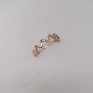 Rose gold wave ring detail shot, minimalist stainless steel jewelry close-up display.