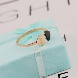 Detailed close-up of a rose gold titanium steel double heart open ring with black acrylic.