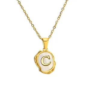 Gold stainless steel necklace detail showing mother of pearl irregular letter C pendant.