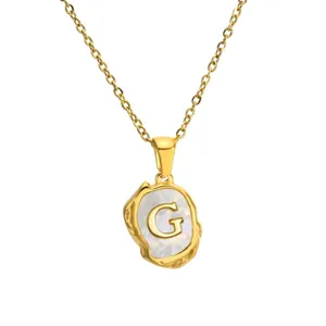 Close-up detail of gold stainless steel necklace featuring mother-of-pearl letter G pendant.