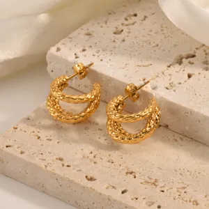 Detail shot of textured double gold hoop earrings on stone display. Elegant jewelry photography.