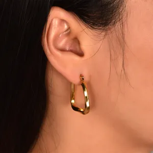 Close-up of the geometric twisted gold hoop earring worn on the ear, showing titanium steel detail.