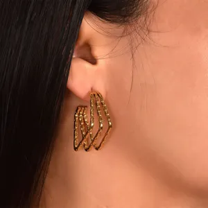 Gold multi-line C-shaped hoop earrings, elegant twisted wave design, fine jewelry detail shot.