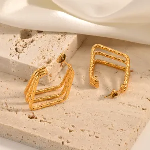 Close-up detail of textured 3-line C-shaped gold hoop earrings, elegant minimalist style.
