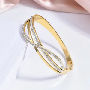 Close-up detail of the luxury gold-plated crossover rhinestone bangle bracelet, polished finish.