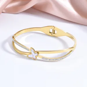 Bracelet jonc double en acier inoxydable doré avec papillon en nacre et cristaux étincelants.