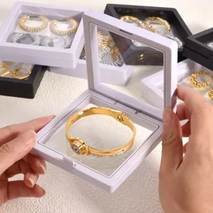 Close-up detail view of transparent PE film jewelry storage box holding a golden accessory.