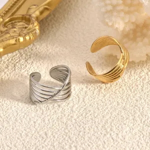 Close-up detail of multi-layer cross open rings in gold and silver titanium steel style.