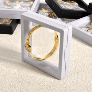 Transparent floating 3D jewelry display box with elastic film for secure storage of bangles.
