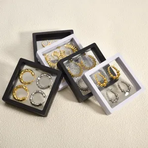 Transparent film jewelry display box detail showing earrings inside square storage frames.