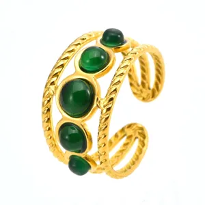 Detail view of a luxury gold stainless steel ring featuring green round resin stones and cable band.