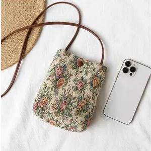 Detailed view of vintage ethnic tapestry crossbody bag with brown leather strap and button closure.
