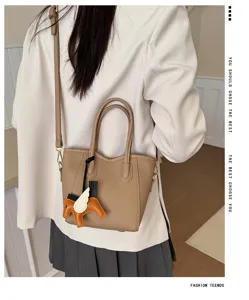 Borsa a secchiello in pelle beige con ciondolo cavallo alato per look chic quotidiano