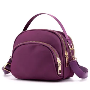 Purple nylon mini dome crossbody bag detail, gold hardware zipper and adjustable shoulder strap