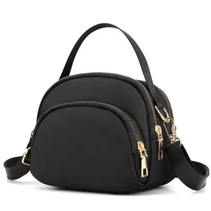 Detailed view of the black nylon mini shell crossbody bag featuring golden zippers and handle.