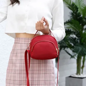 Close-up view of the red nylon shell crossbody bag, showing fine zipper and strap details.