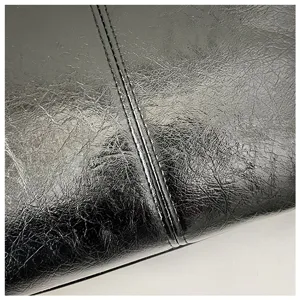 Detailweergave van de zwarte gekreukte PU-ledertextuur en precieze stiksels op de damestas.