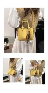 Korean style yellow soft leather bucket bag with cute bear pendant, stylish crossbody design.