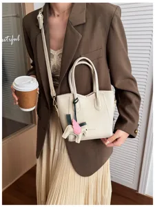 Primo piano dettaglio della borsa a secchiello casual elegante con ciondolo cavallo alato e tracolla.