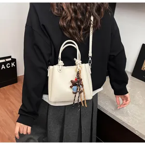 Detailed view of a stylish soft leather bucket bag featuring a cute bear pendant and strap.