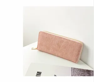 Detalle de una elegante cartera rosa de ante sintético con cremallera y herrajes dorados.