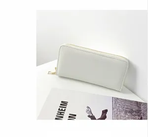 Detalle de la cartera larga blanca de mujer con cuero sintético liso y cremallera dorada.