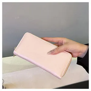 Vista dettagliata di un portafoglio rosa con cerniera in mano, elegante e liscia finitura.