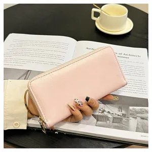 Vista dettagliata di un elegante portafoglio rosa con zip sopra un libro aperto.