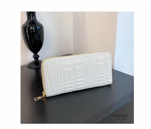 Detail shot of white quilted long wallet purse with gold zipper and card slots interior.