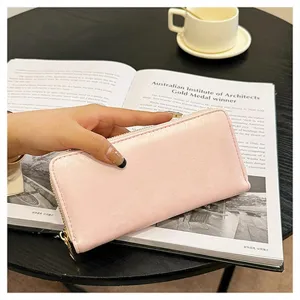 Primo piano dettagliato del portafoglio lungo in pelle rosa con cerniera e scomparti.