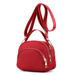 Detail view of the mini red nylon shell crossbody bag, highlighting zippers and hardware.