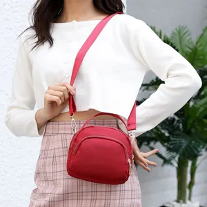 Detailed shot of the red nylon mini crossbody bag worn by model, showing zipper and strap.