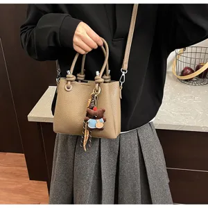 Detailed view of a stylish Korean style bucket bag with cute bear charm and soft leather material.