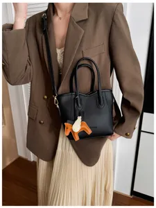 Vista dettagliata della borsa a spalla in pelle nera con ciondolo ad ala elegante.