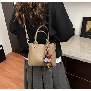 Detailed shot of a soft leather bucket shoulder bag with cute bear pendant for daily commute.