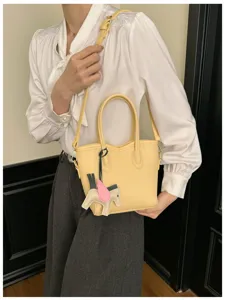 Vista di dettaglio di una borsa a secchiello gialla coreana casual con ciondolo cavallo alato.