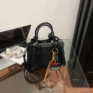 Stylish black leather bucket bag for women with cute bear pendant, versatile crossbody.