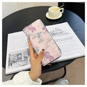 Gros plan sur le portefeuille long rose avec motif floral en relief et fermeture à glissière.
