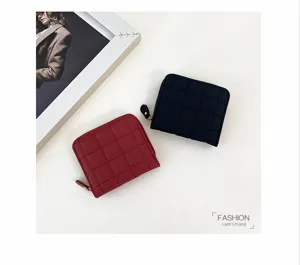 Gros plan de petits portefeuilles zippés minimalistes avec texture matelassée à carreaux.