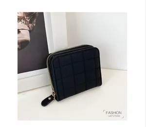 Portefeuille court matelassé noir classique avec fermeture éclair et design à carreaux.