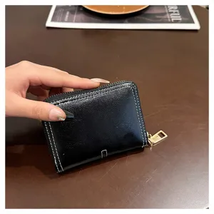 Dettaglio di mini portafoglio con zip nero, porta carte in pelle morbida, piccolo borsellino.