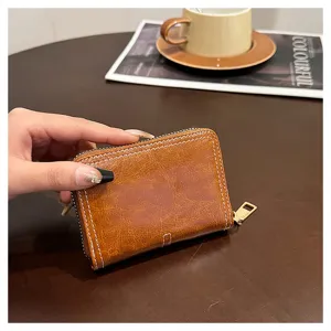 Primo piano dettagliato di un mini portafoglio in pelle marrone con chiusura lampo e cuciture.