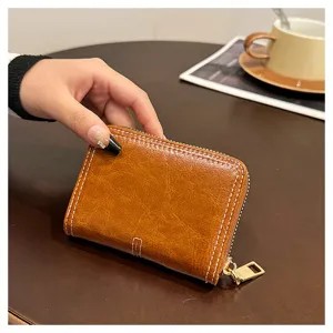 Vista dettagliata di un portafoglio corto marrone in pelle compatto con cuciture e zip dorata.