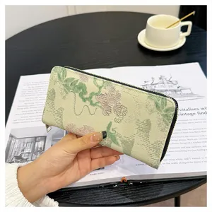 Détail de long portefeuille en brocart floral, texture élégante et fermeture éclair sécurisée.