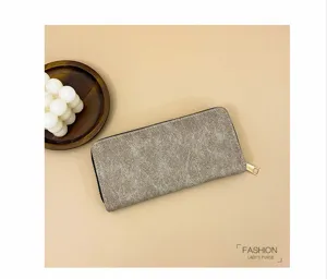 Detalle de cartera larga de mujer estilo retro con textura de cuero y cremallera dorada.