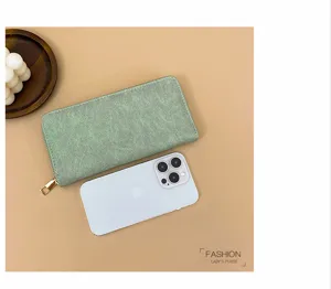 Detalle del elegante monedero largo verde con textura retro y cierre de cremallera.