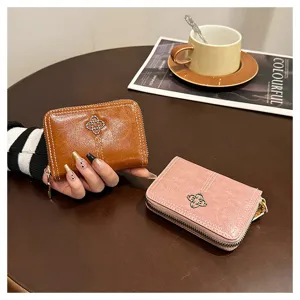 Primo piano di portafogli in pelle corti marroni e rosa con zip e decorazione a trifoglio.
