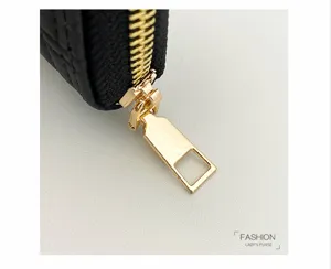Close-up view of a black wallet with smooth golden zipper and elegant square metal puller.